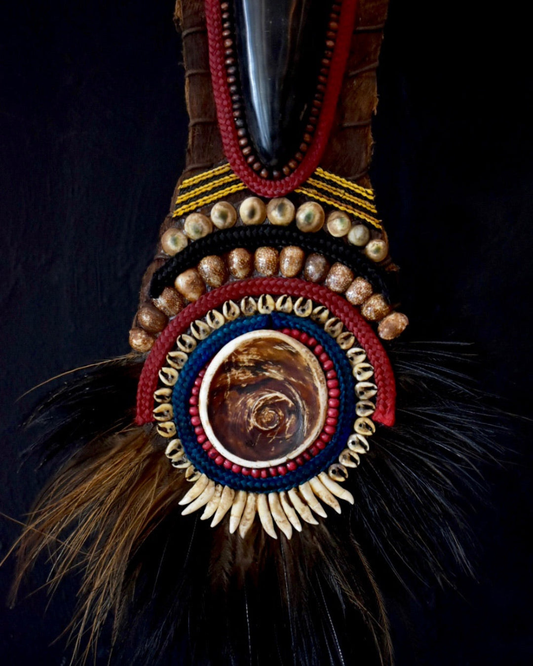 Decorative object with feathers and beadwork on a dark background
