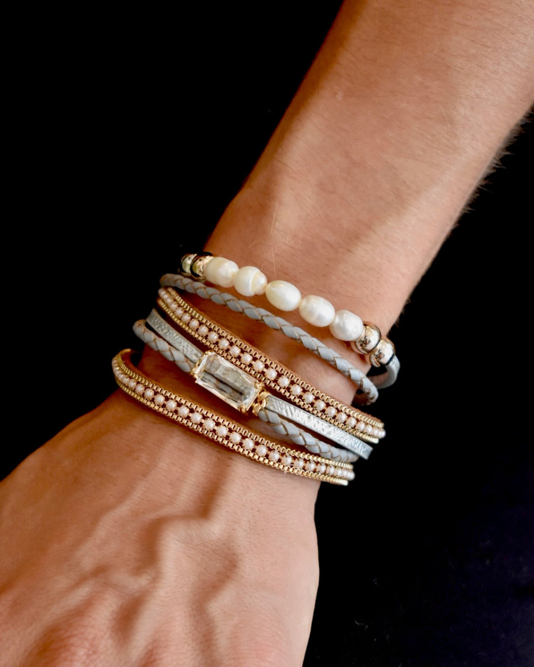 Close-up of a wrist wearing multiple bracelets on a dark background