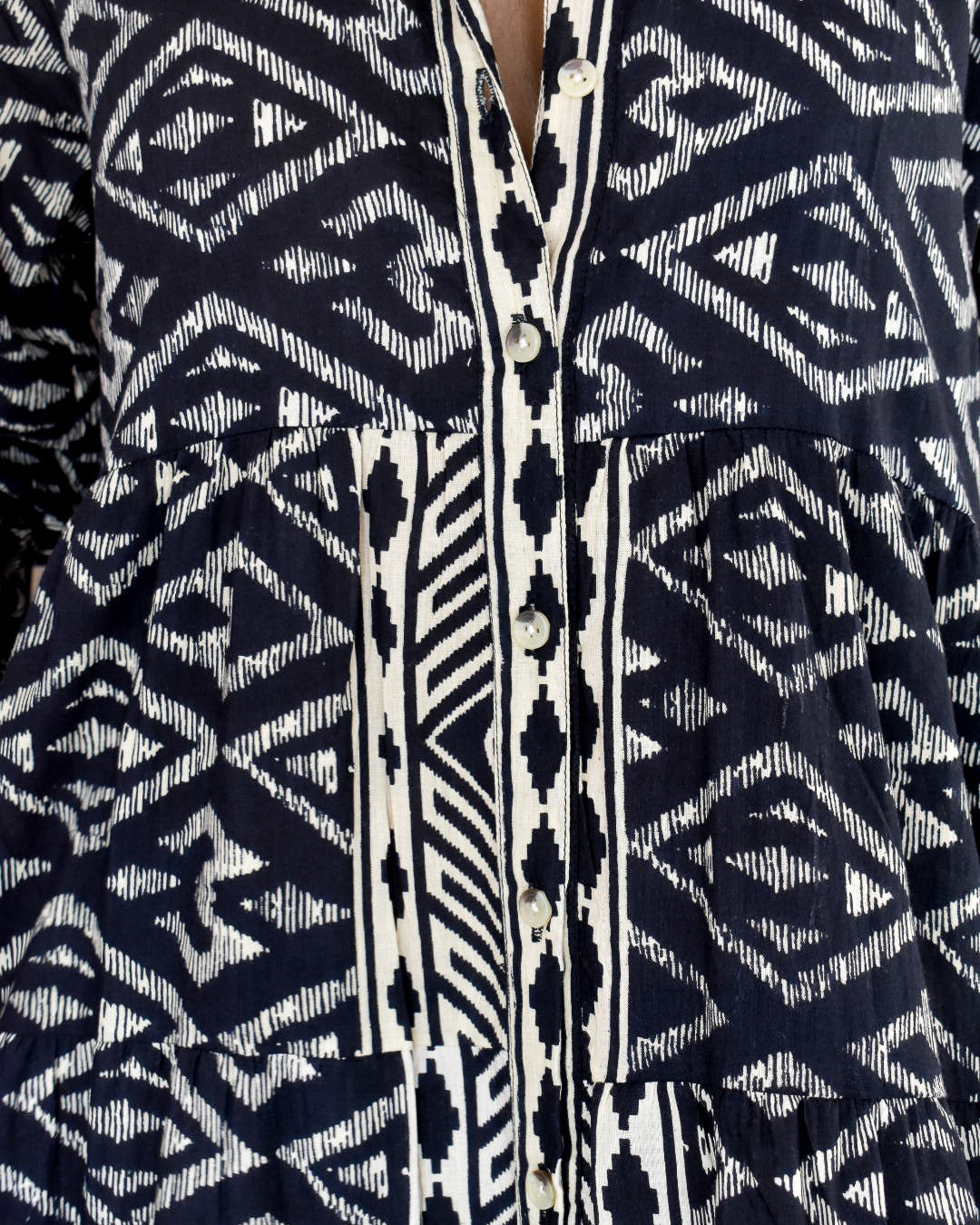 Close-up of a navy and white patterned shirt with buttons.