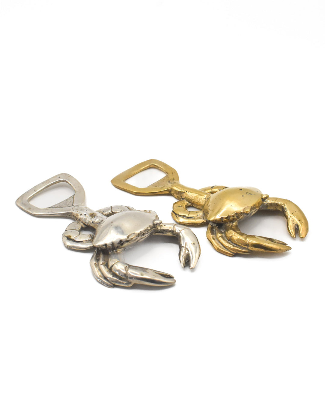 Two crab-shaped bottle openers, one silver and one gold, on a white background.