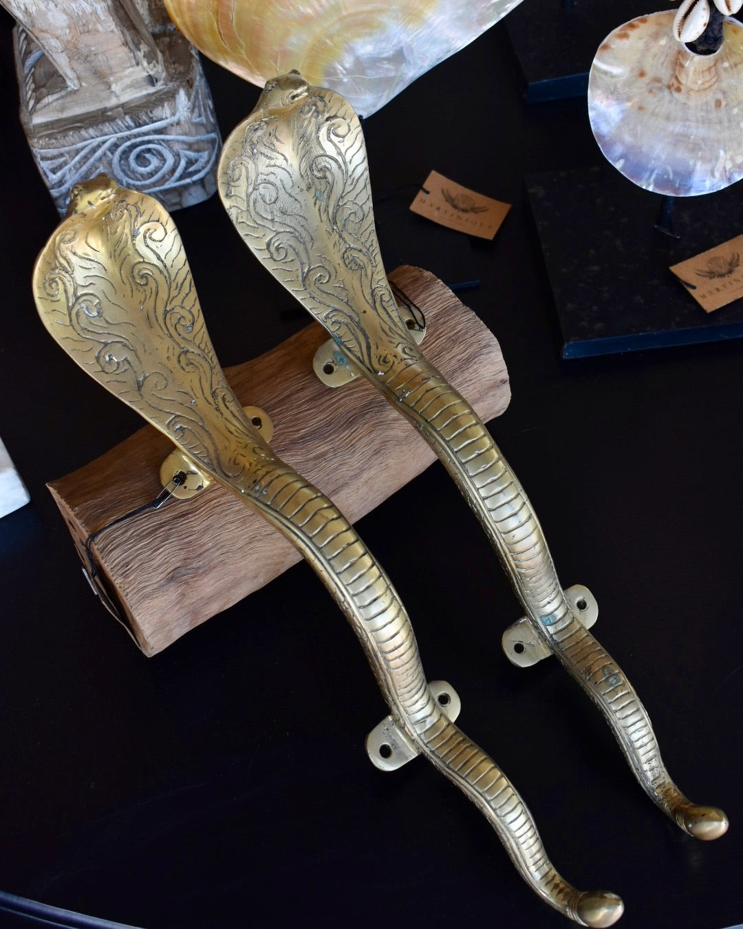 Decorative brass snake-shaped door handles on a dark surface.