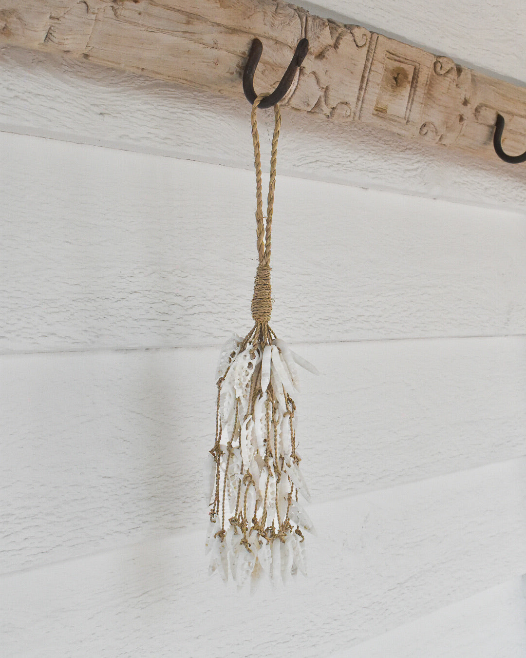 Decorative hanging with beads and rope against a white wall