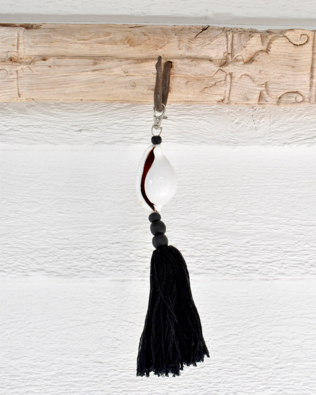 Decorative keychain with black tassel and beads on a textured white background