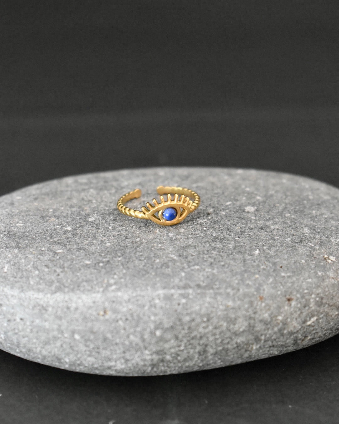 Gold ring with a blue gemstone on a gray stone surface