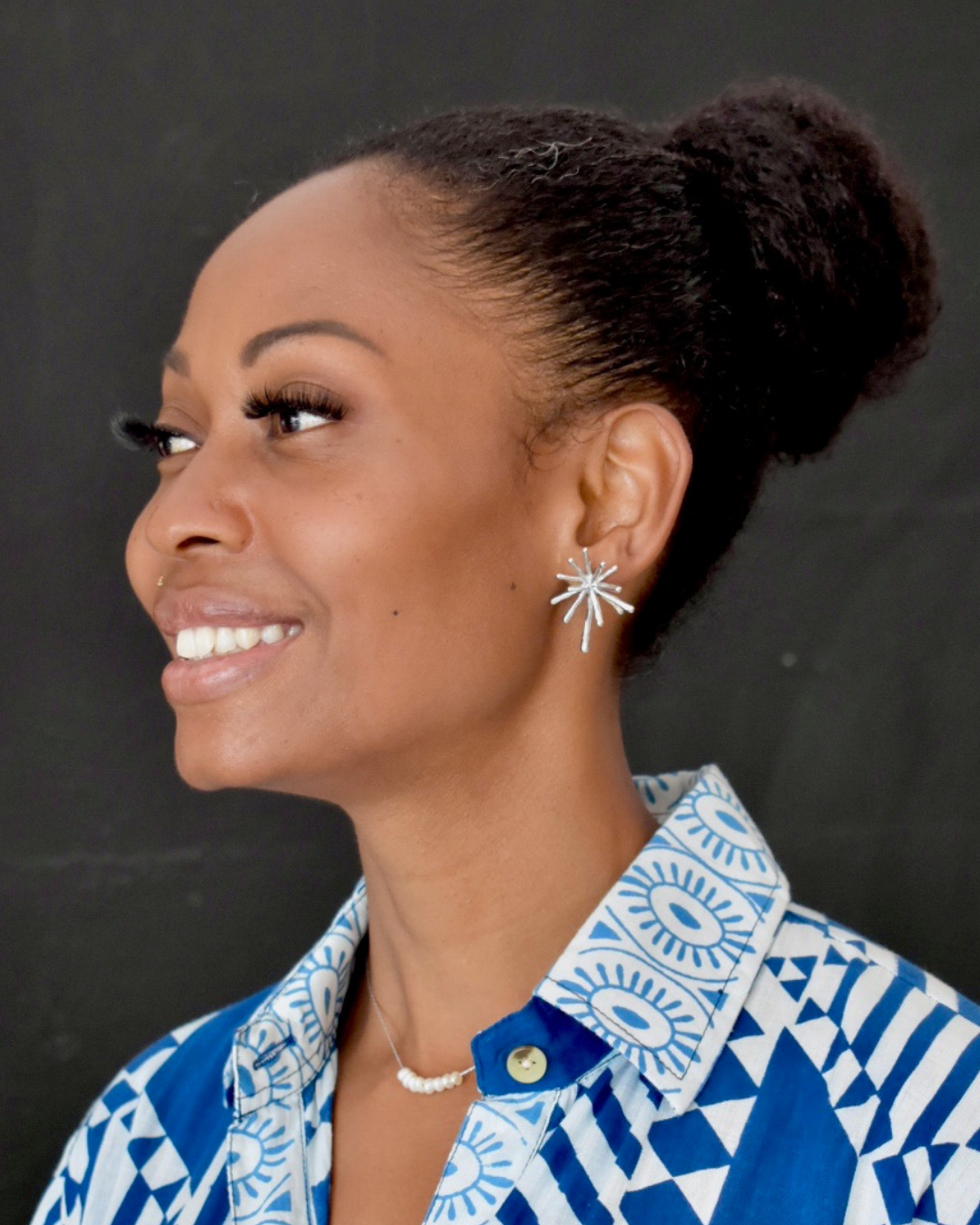 Woman wearing a blue and white patterned shirt with a dark background