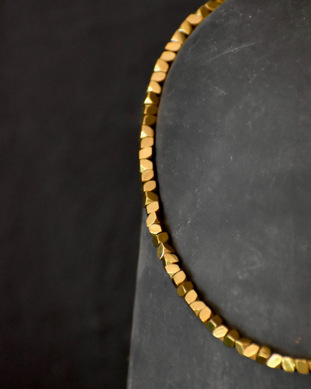 Gold beaded bracelet on a dark surface