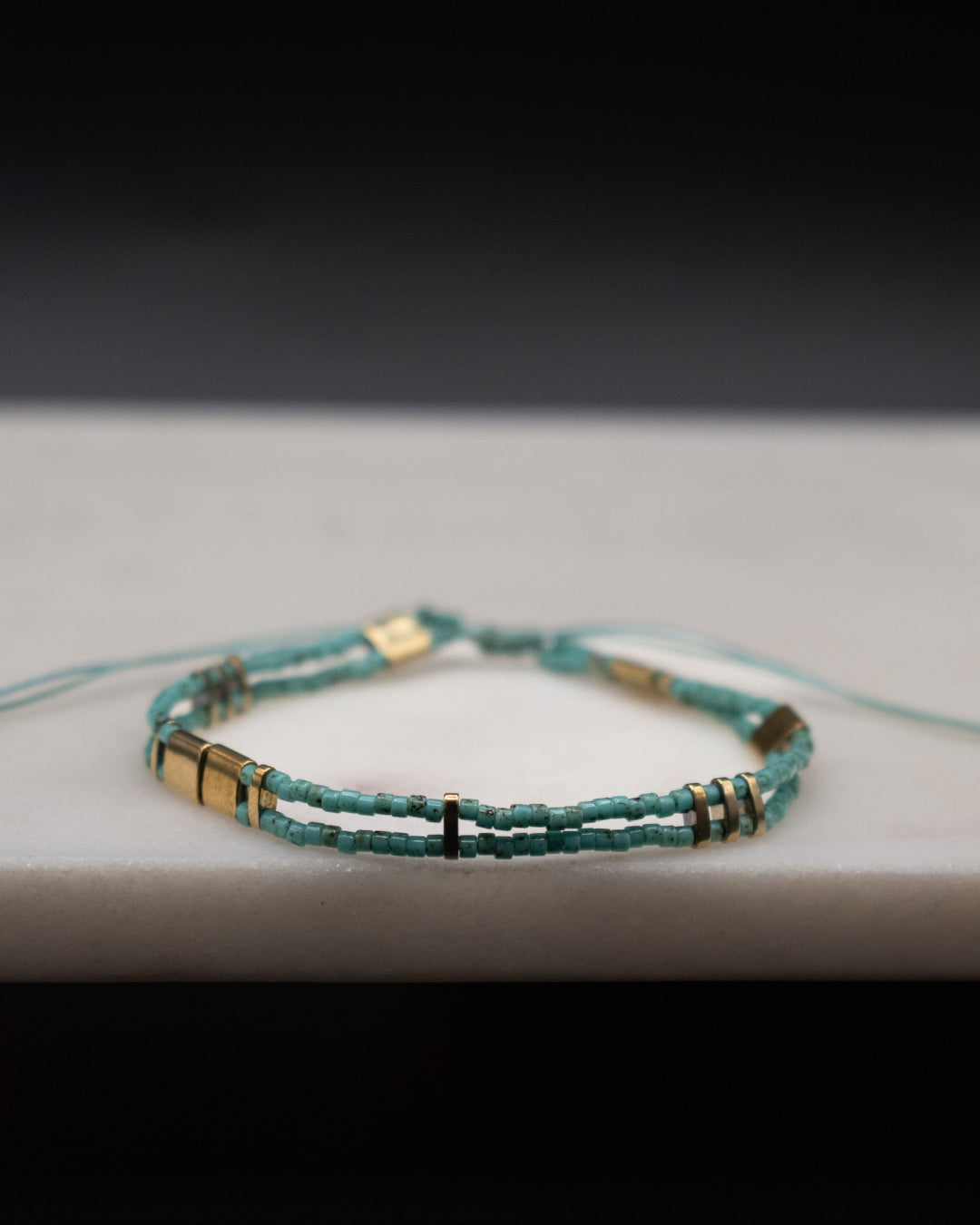 Turquoise beaded bracelet with gold accents on a light surface