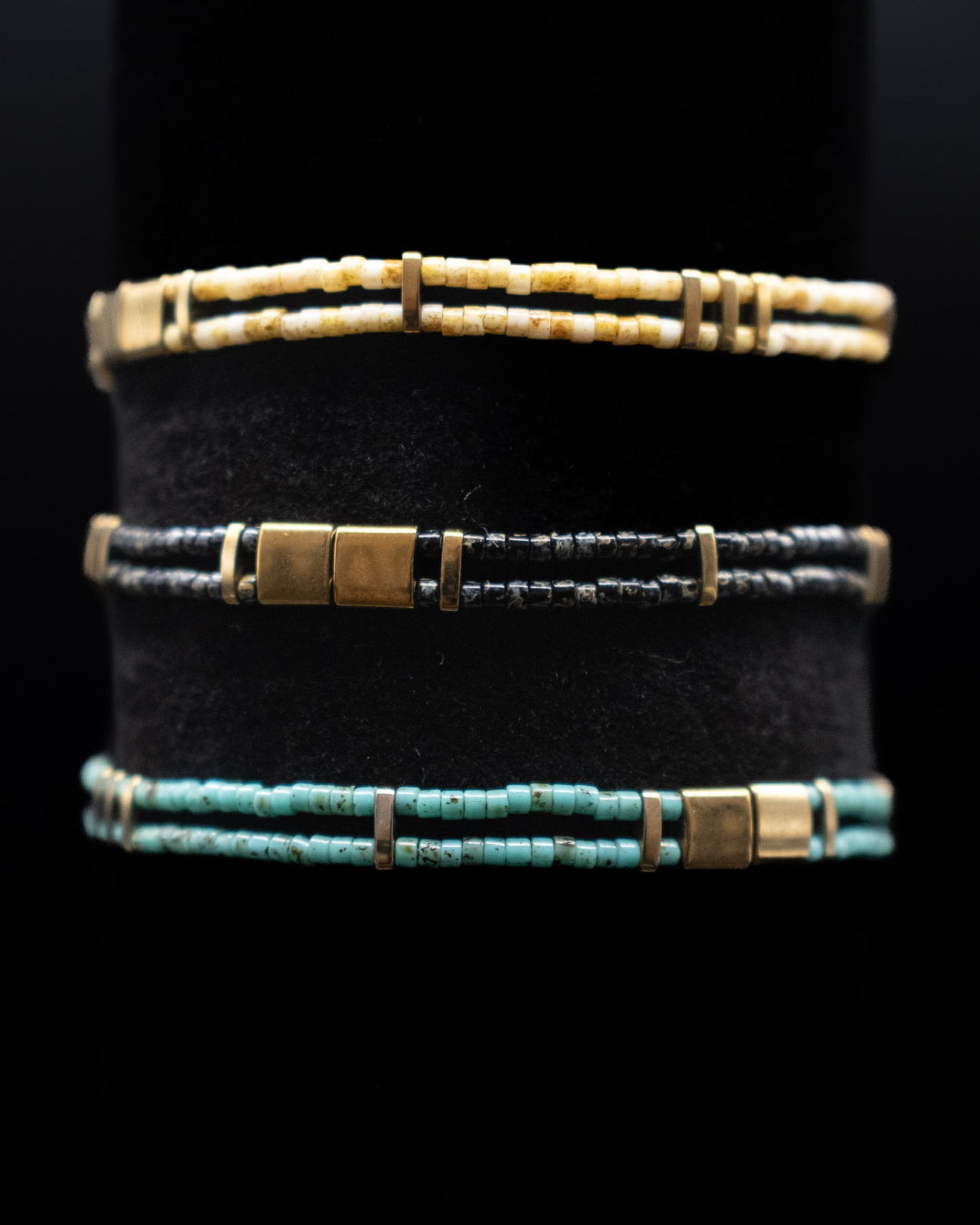 Three bracelets with different color schemes on a black background