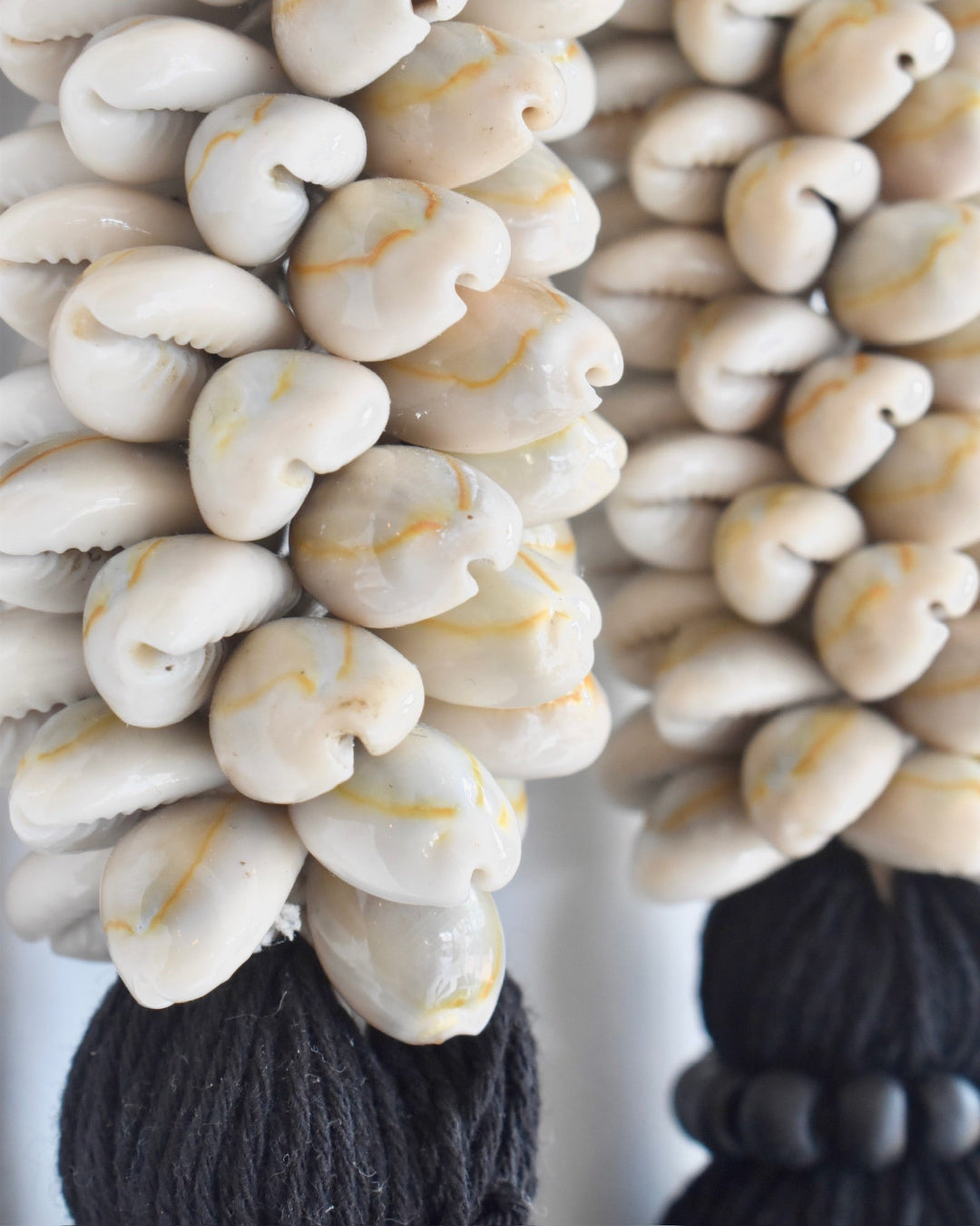 Decorative item with white beads and black yarn on a plain background