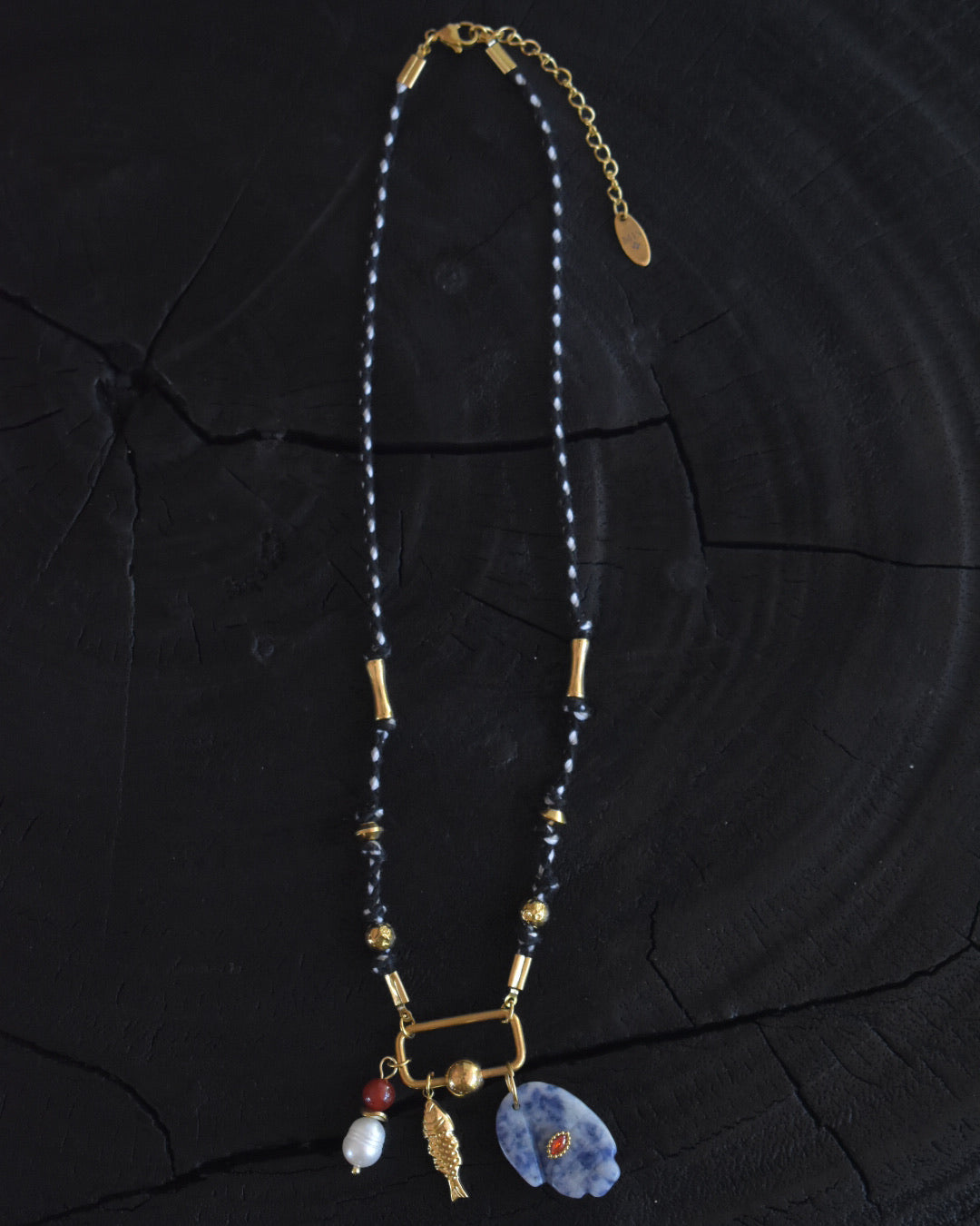 Necklace with blue hand stone pendant and gold accents on a dark wooden surface