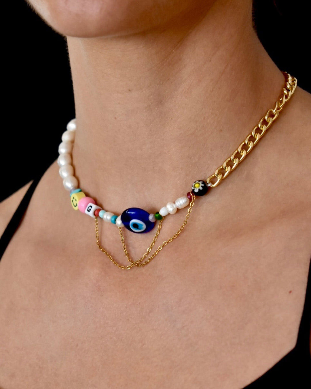 Necklace with colorful beads and gold chain on a person against a black background