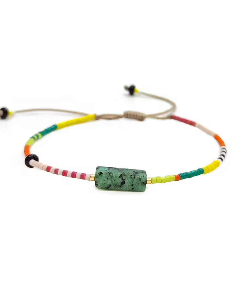 Colorful beaded bracelet with a green stone on a white background