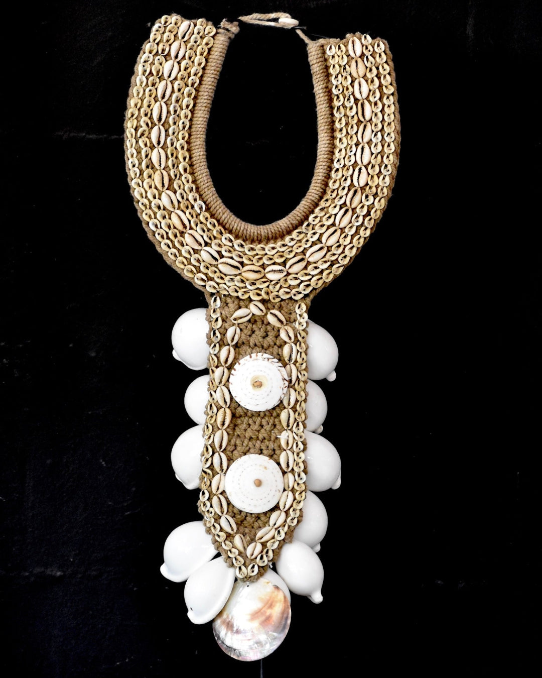 Decorative necklace with gold chain and white beads on a black background