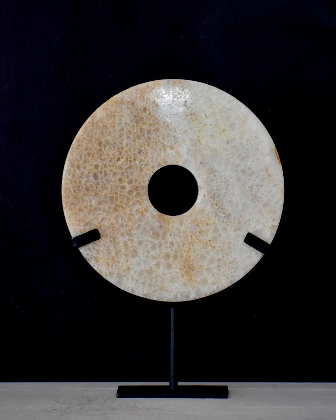 Decorative stone disc on a stand against a black background