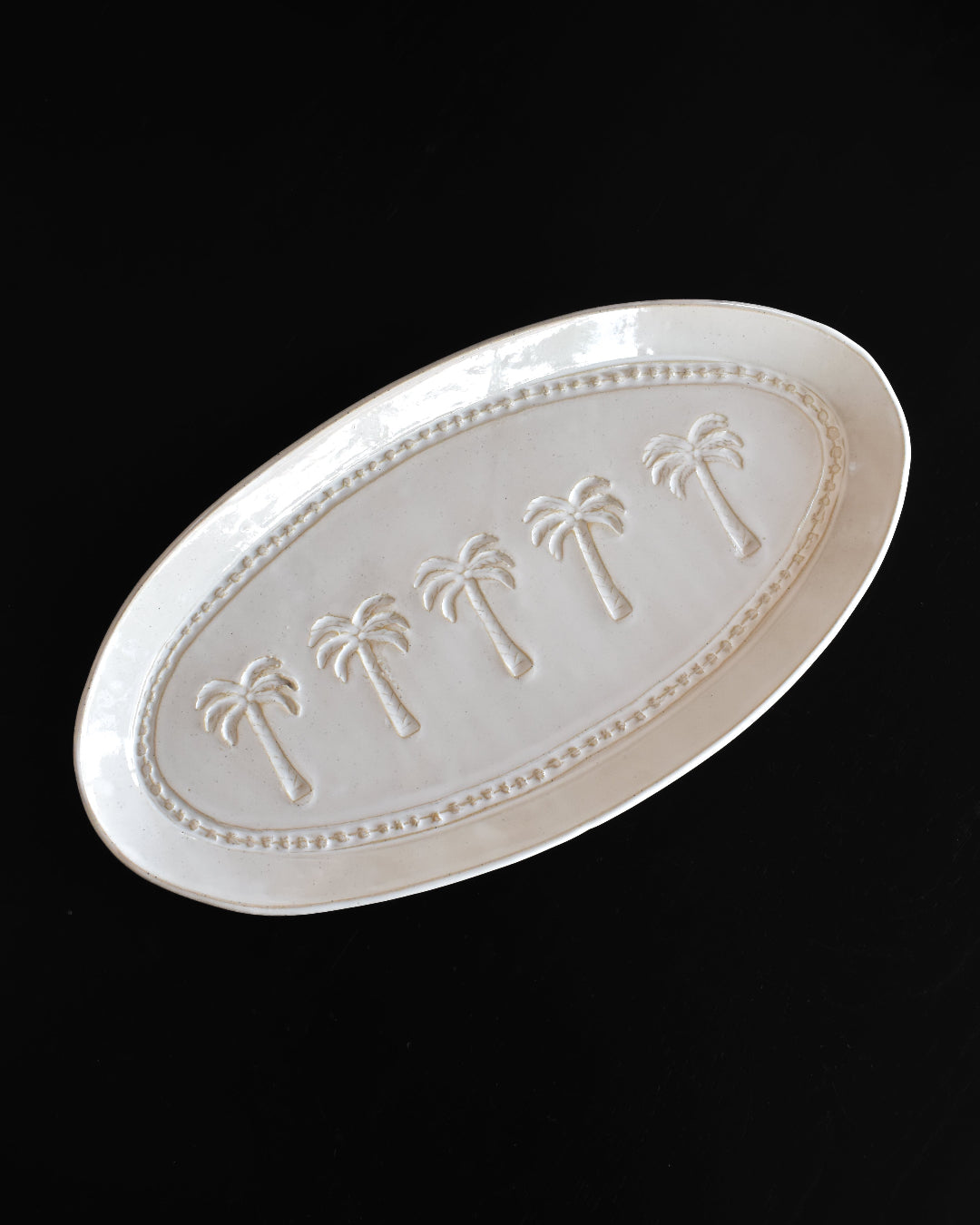 White ceramic platter with palm tree designs on a black background