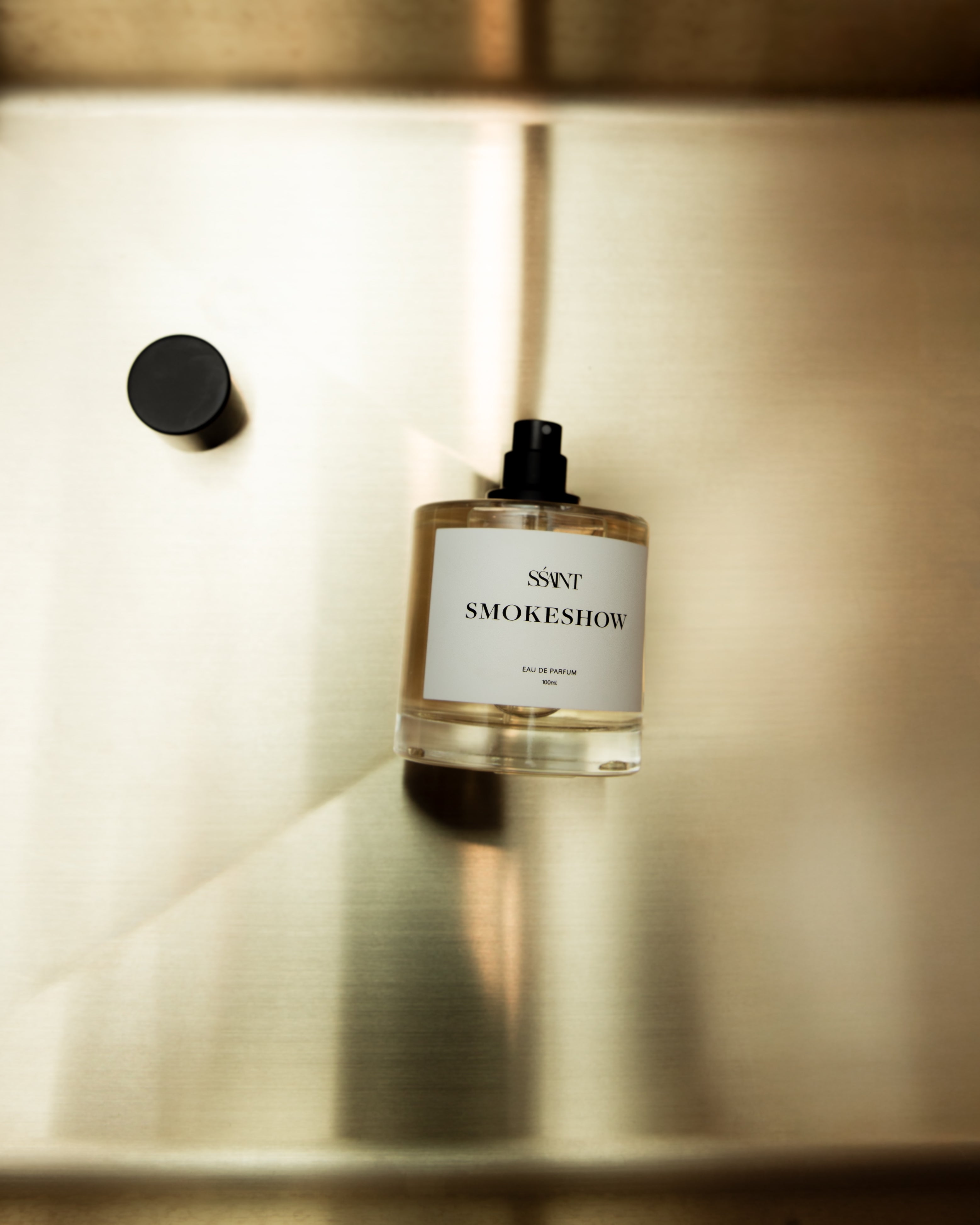 Scented bottle labeled 'SMOKESHOW' on a metallic surface with soft lighting.