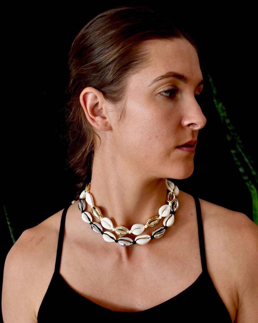 Woman wearing a shell necklace against a dark background
