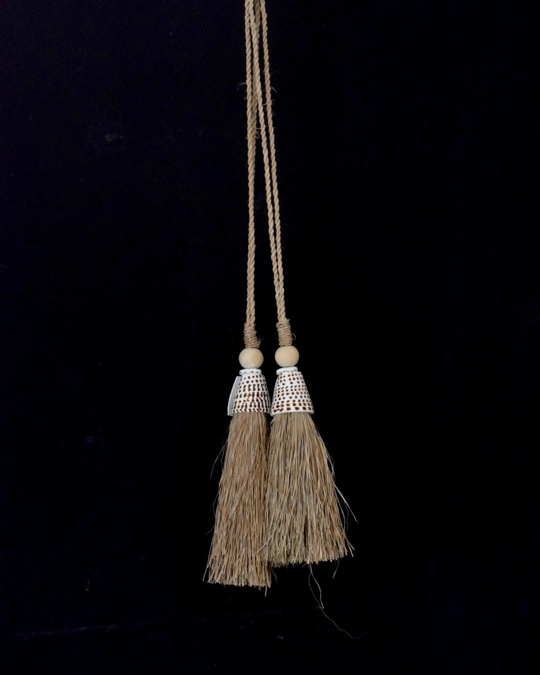 Two tassels with decorative beads hanging against a black background