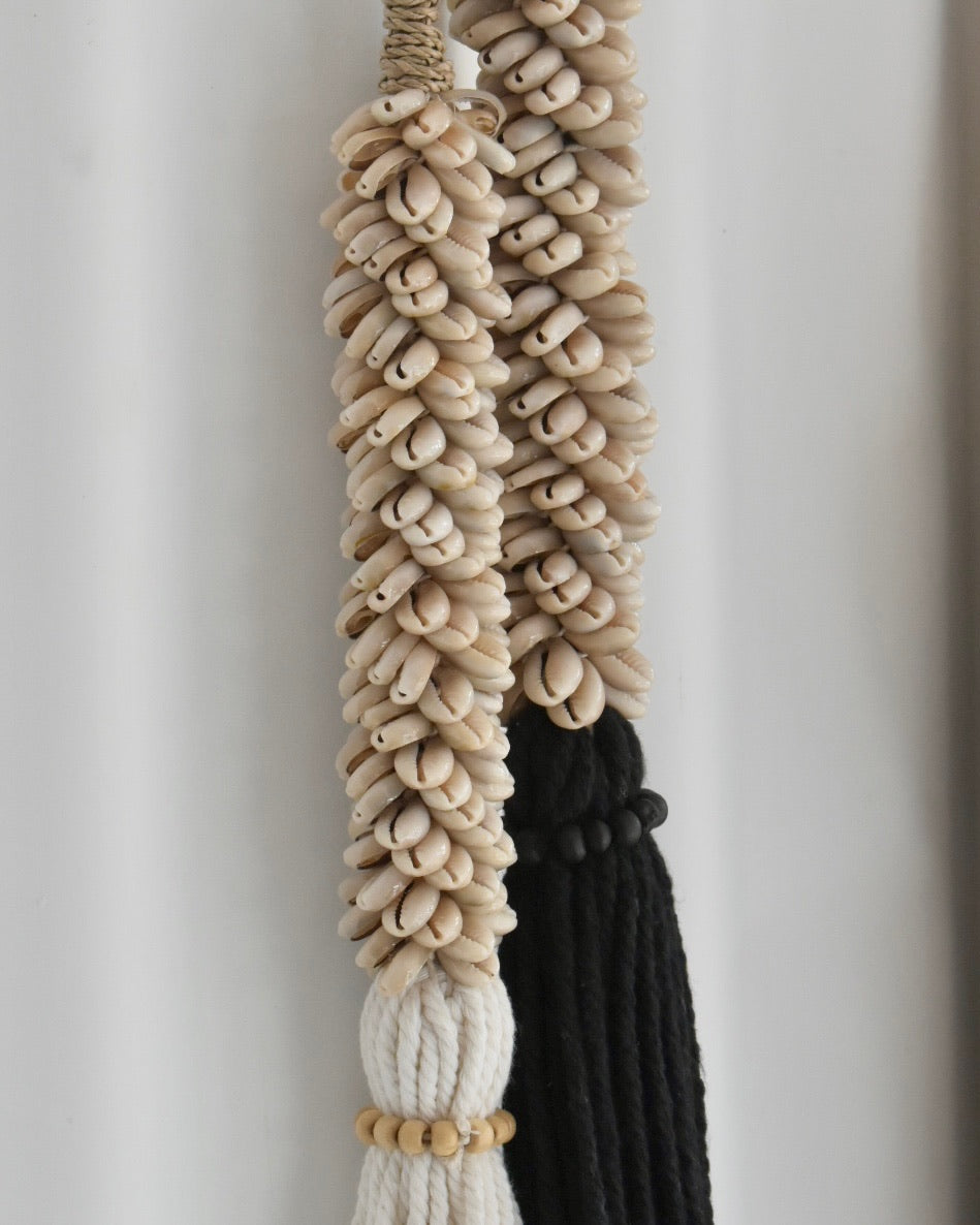 Decorative wall hanging with braided rope and beads on a plain background