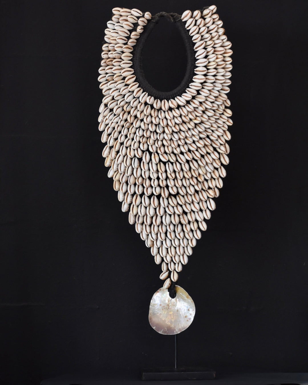 Shell necklace with a central pendant on a black background