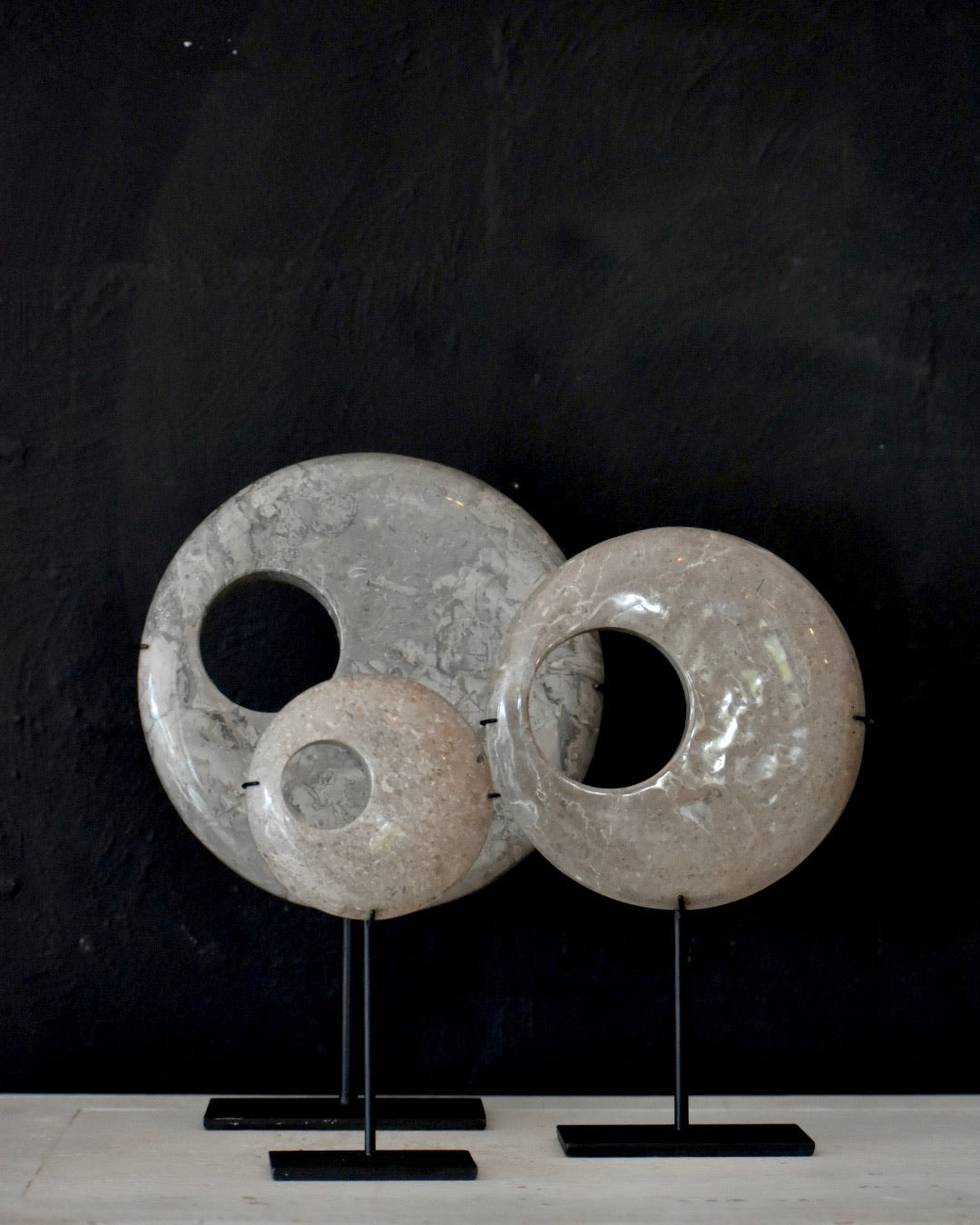 Three marble stone rings on stands against a dark background