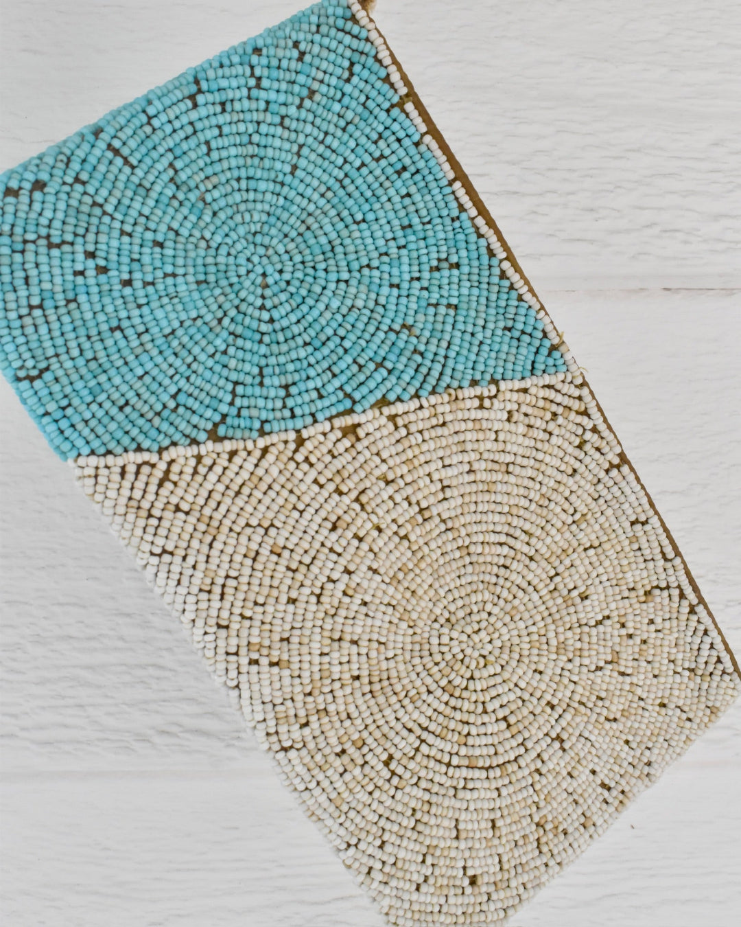 Beaded clutch with turquoise and beige patterns on a light wooden surface