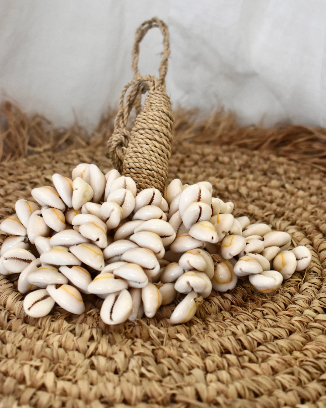 Pile of white seashells on a woven mat with a rope handle in the background