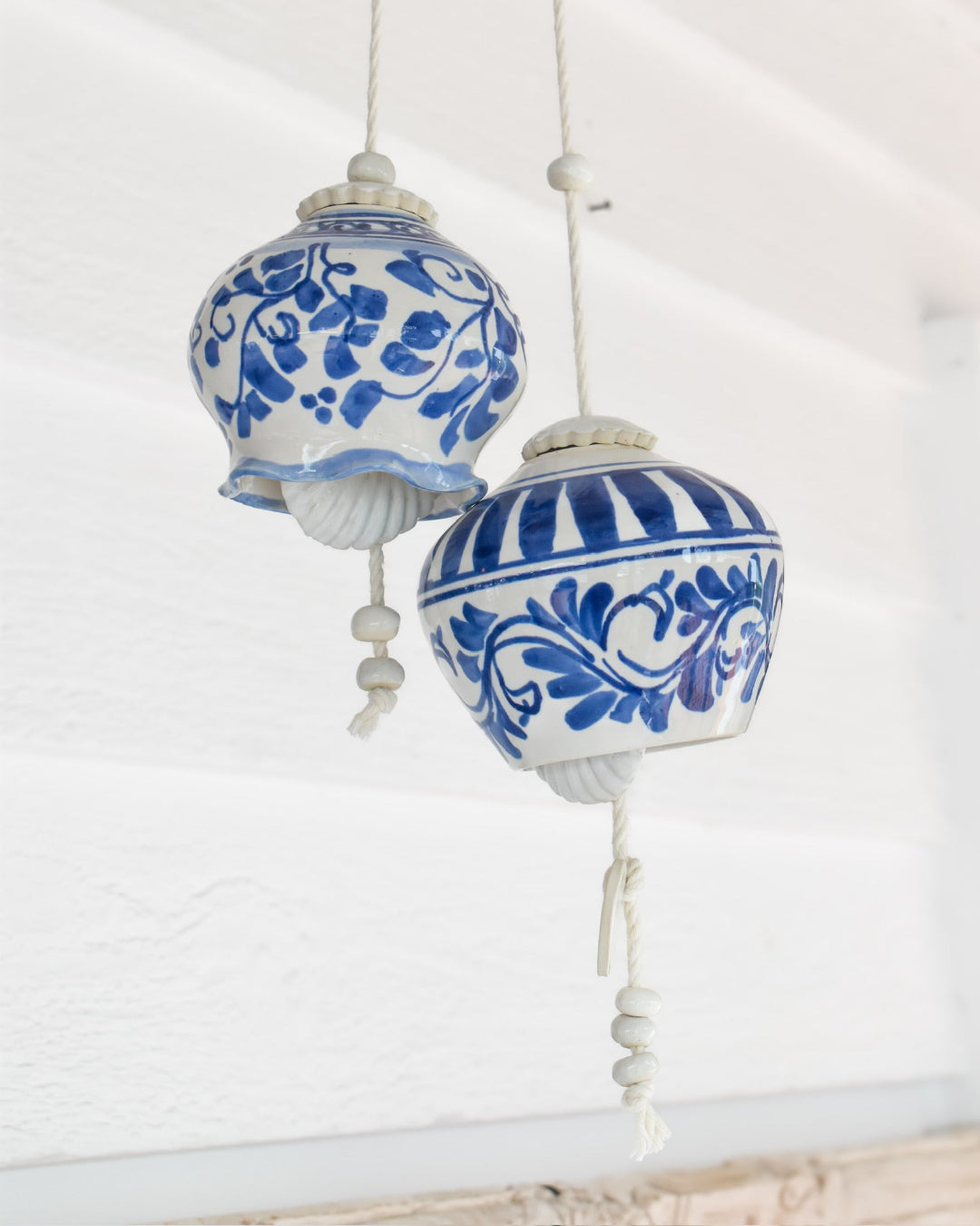 Two blue and white ceramic light fixtures hanging against a white background