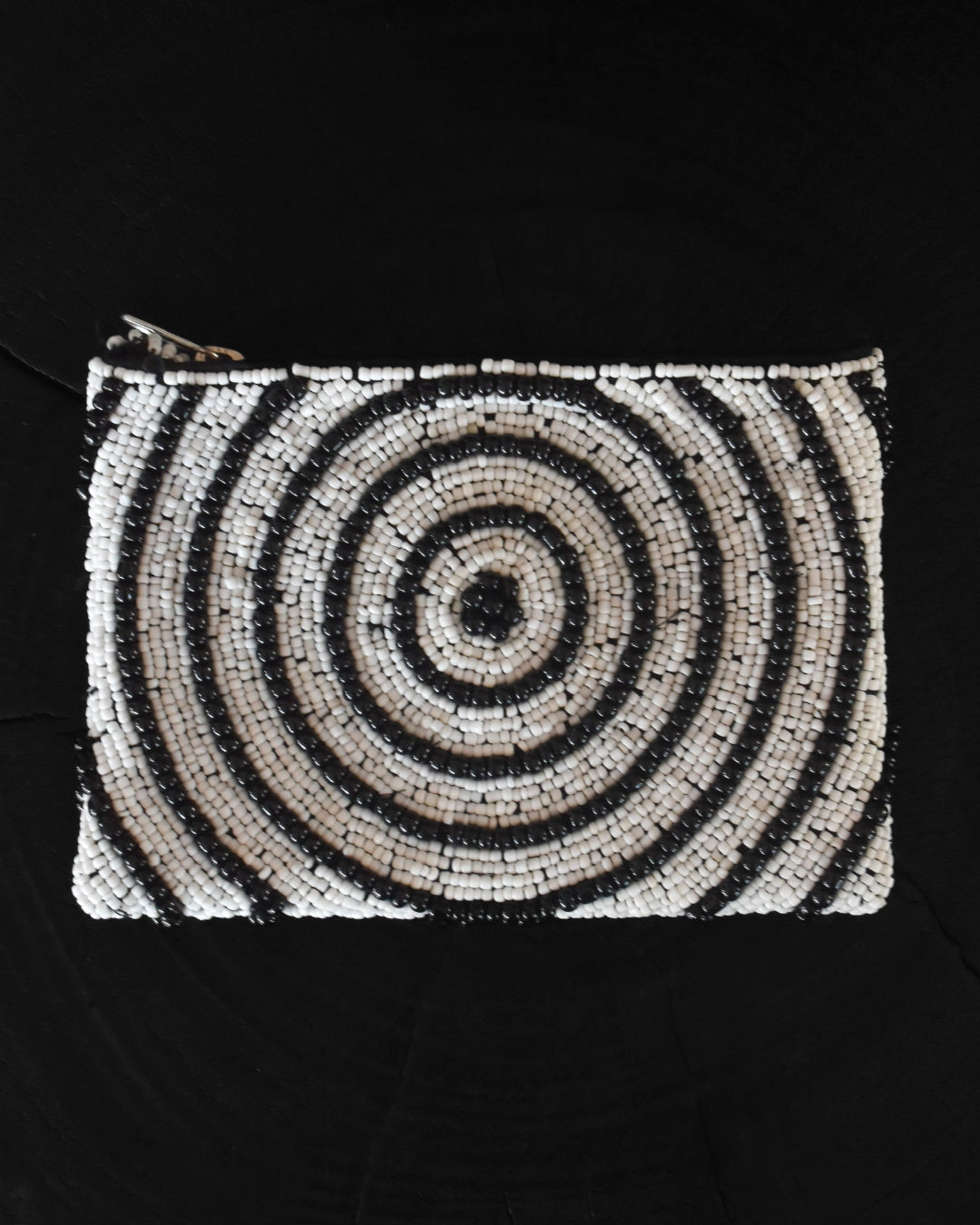 Black and white spiral patterned pouch on a black background