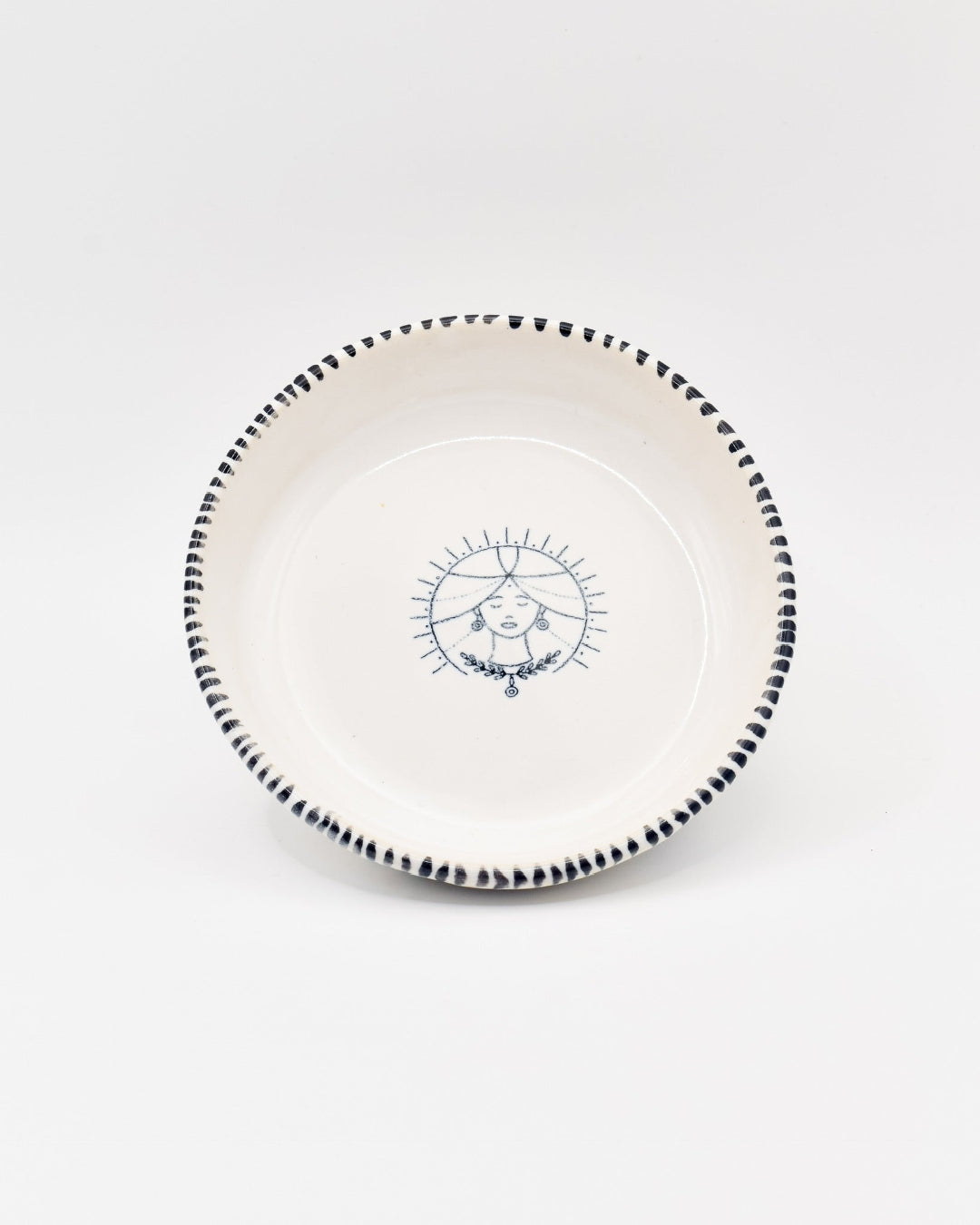 White plate with black rim and decorative blue design on a white background