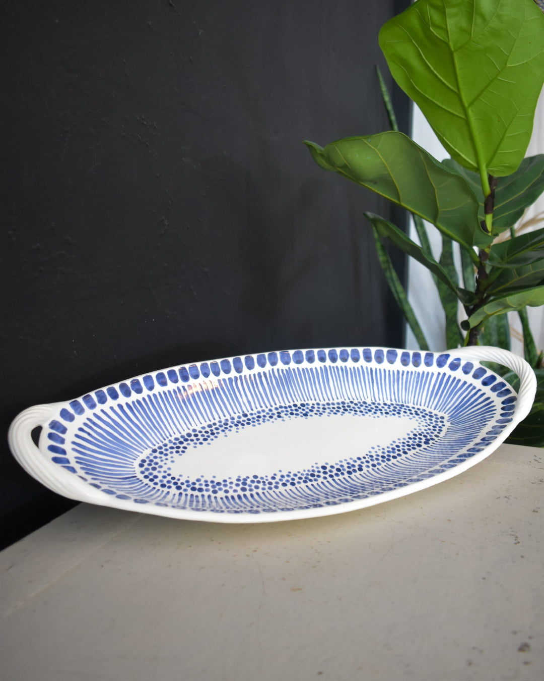Oval ceramic platter with blue patterns on a dark background
