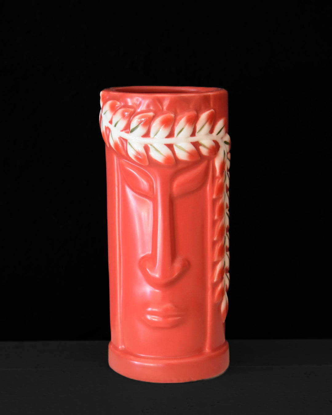 Red tiki mug with a face design on a black background