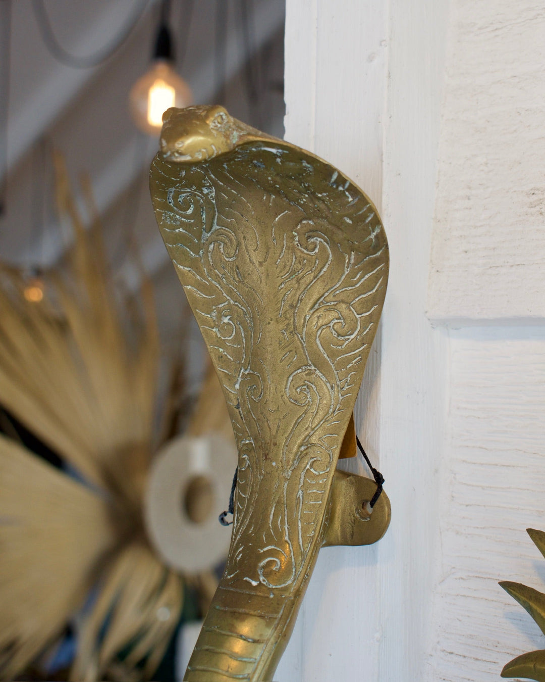 Decorative gold snake-shaped object against a white wall.