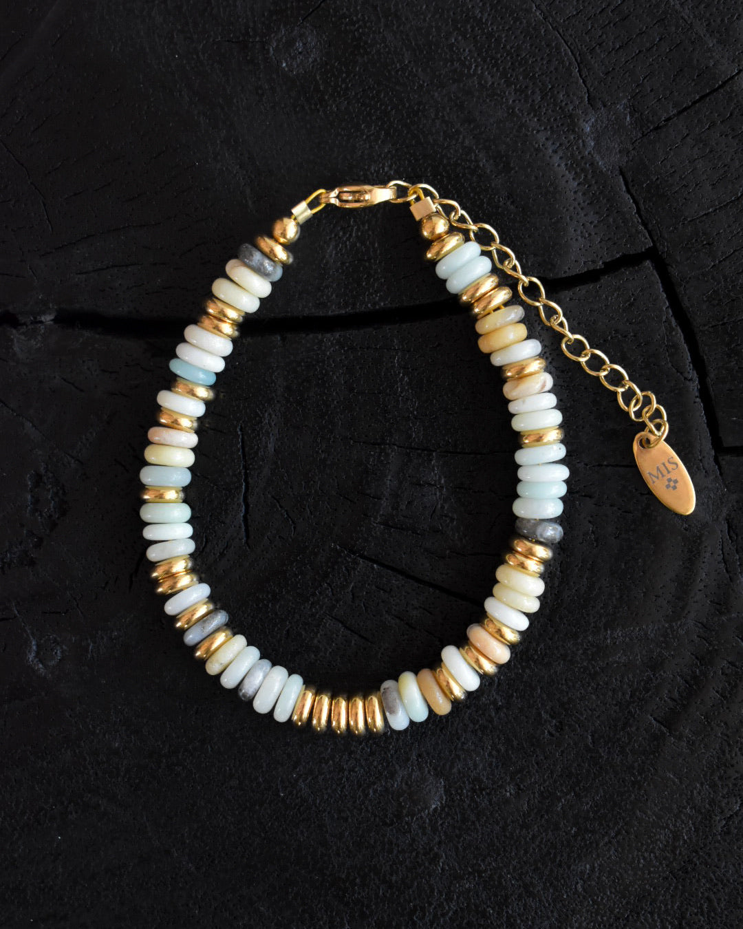 Bracelet with gold and white beads on a dark textured background