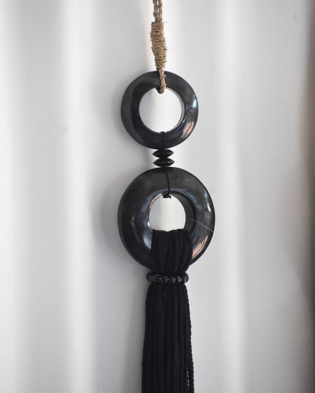Black decorative hanging item with two circular designs on a white background