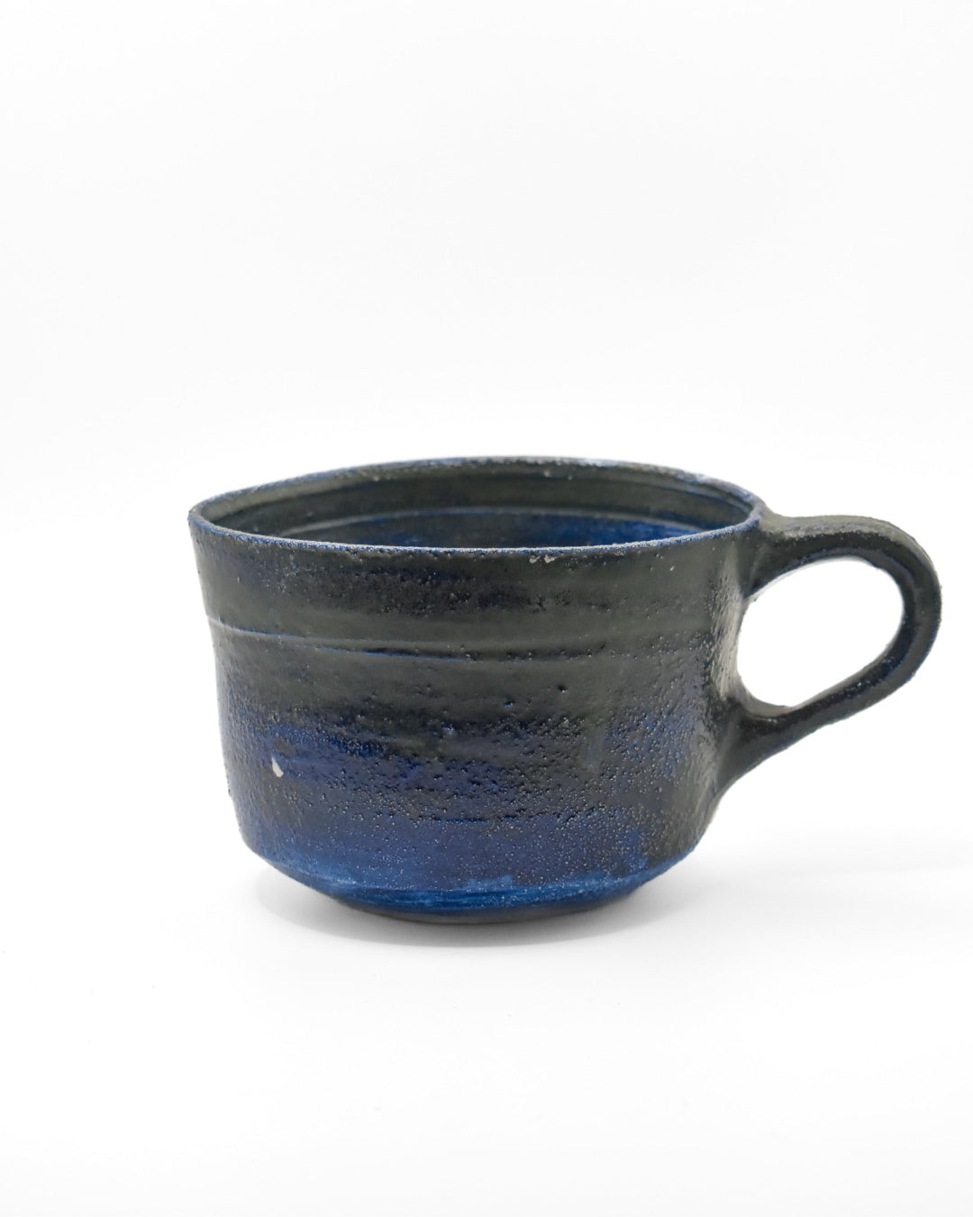 Blue black ceramic mug with blue interior on a white background