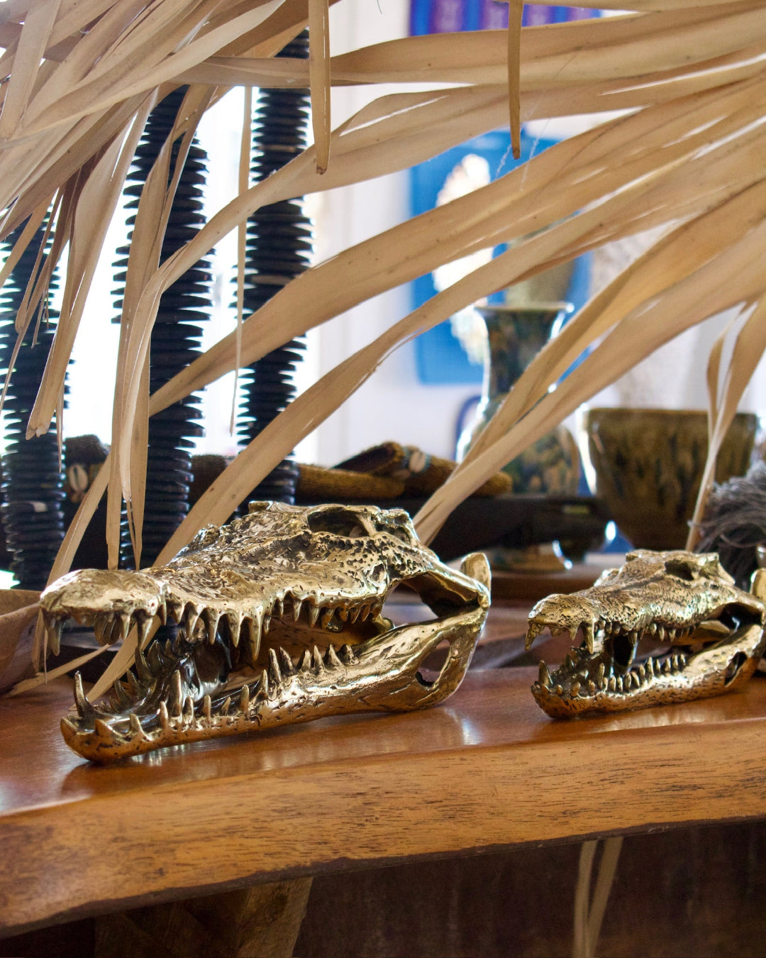 Gold crocodile skulls on a wooden surface with decorative elements in the background