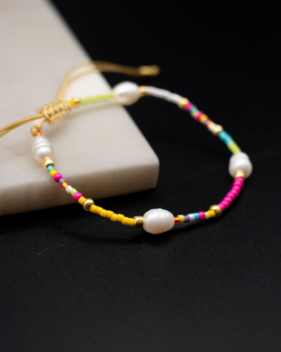 Colorful beaded bracelet with pearls on a dark surface