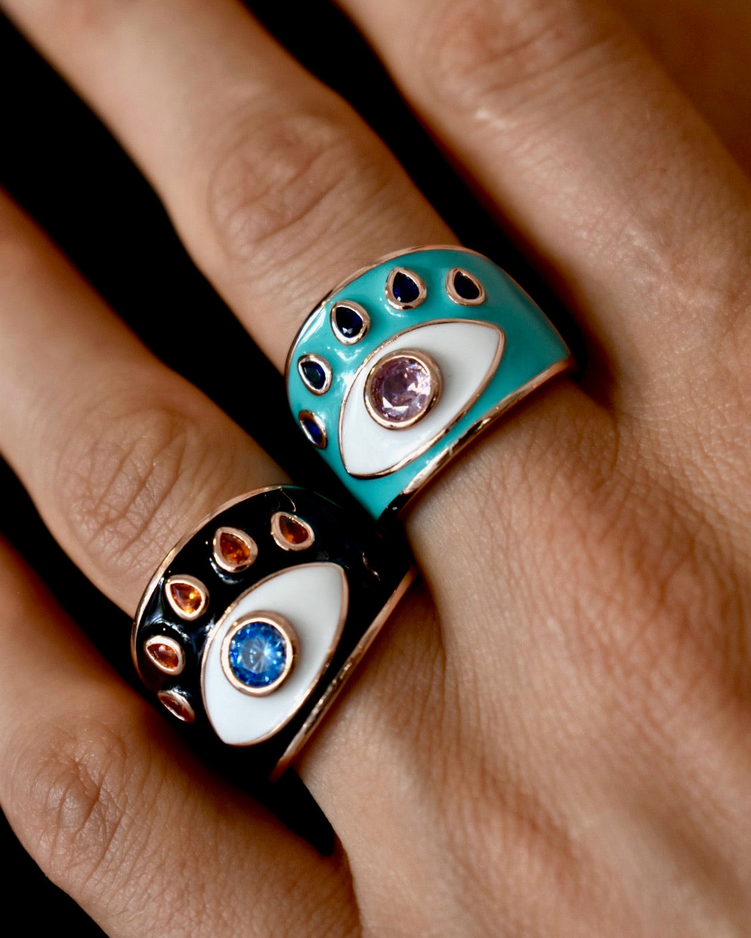 Close-up of a hand wearing two decorative rings with gemstones.