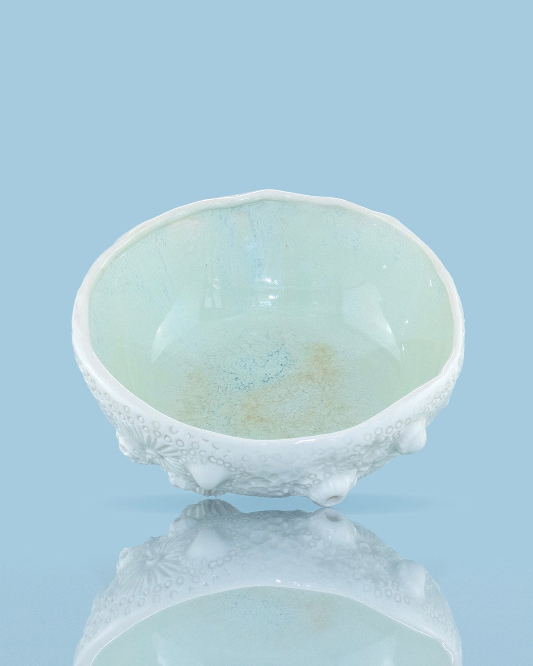 White ceramic bowl with textured base on a light blue background