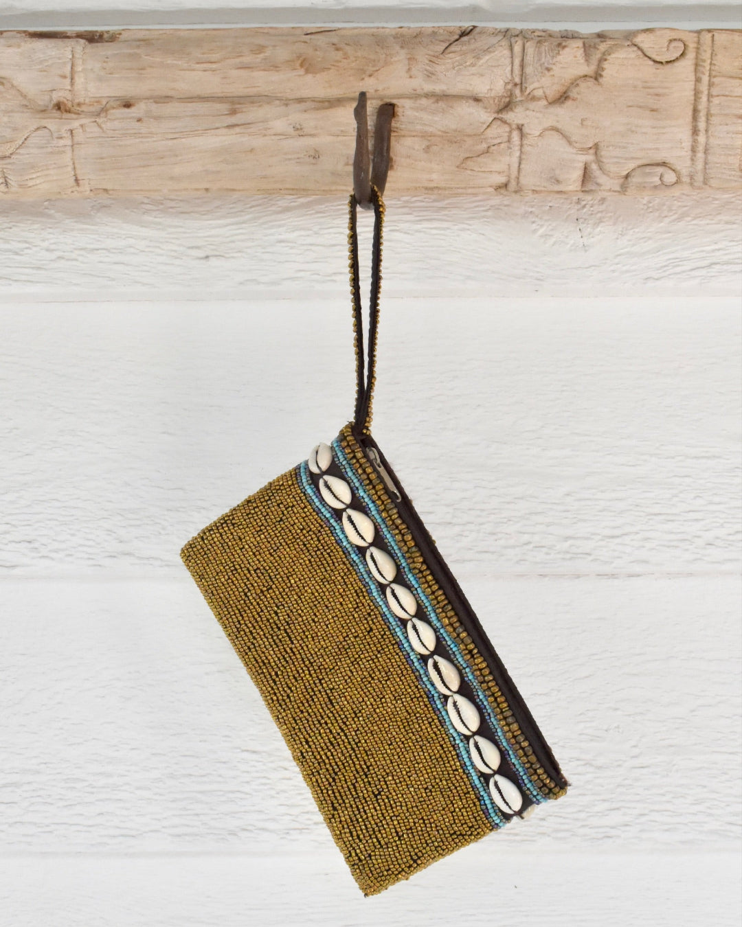 gold beaded clutch with shell embellishments on a wooden surface