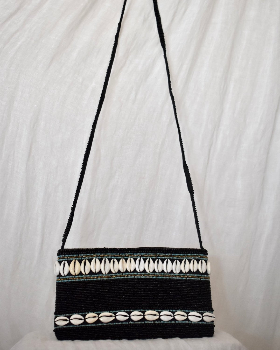 Black handbag with white shell patterns on a white background