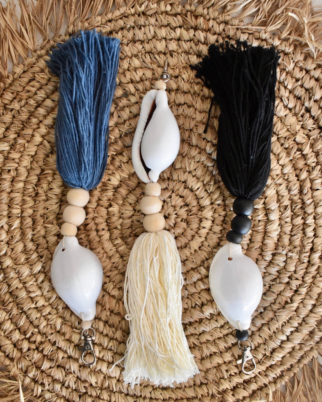 Three decorative keychains with tassels on a woven mat