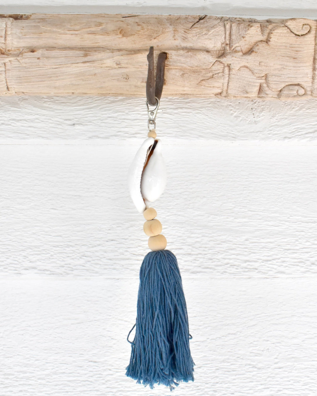 Decorative keychain with blue tassel and beads on a textured surface