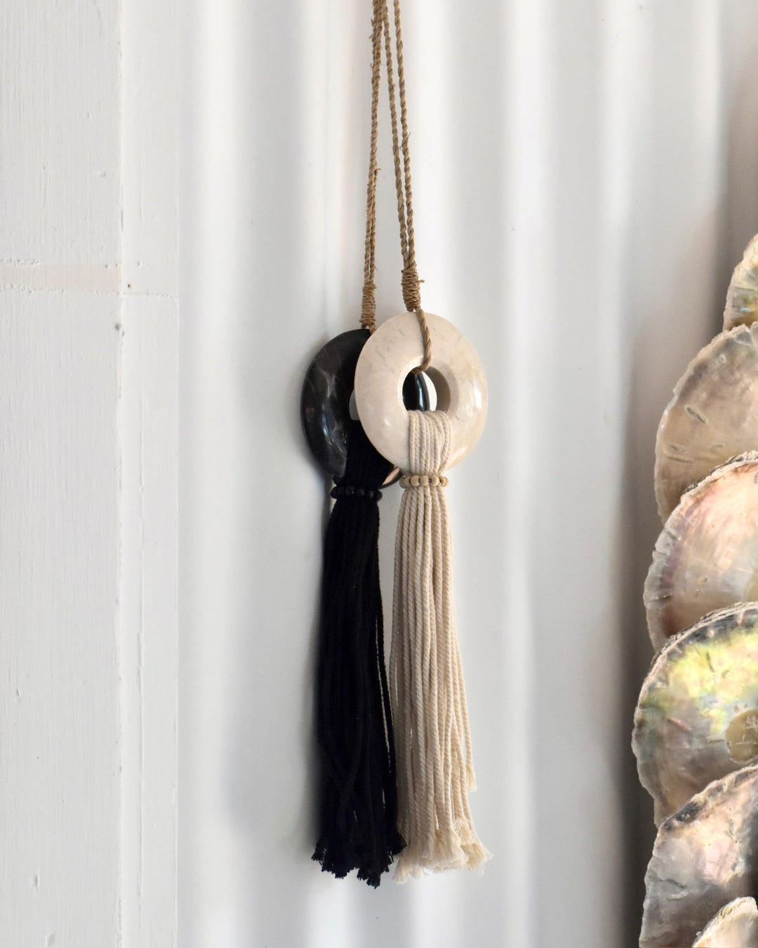 Decorative wall hanging with shell and tassel details on a white background