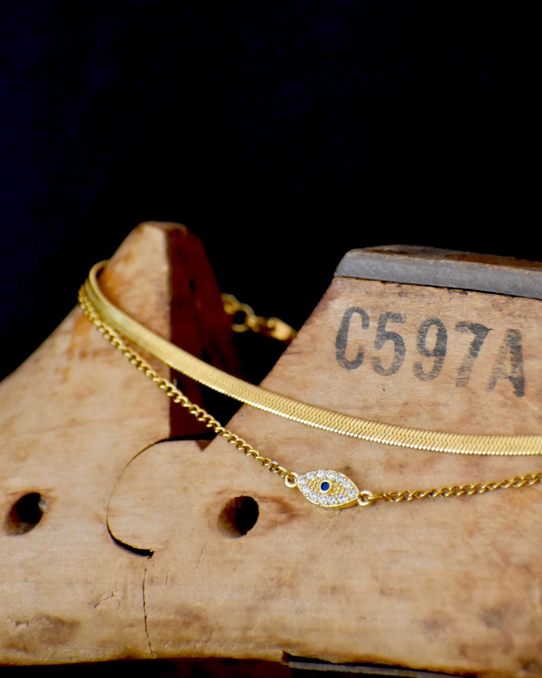 Gold Amkletwith a blue stone eveil eye on a wooden block 