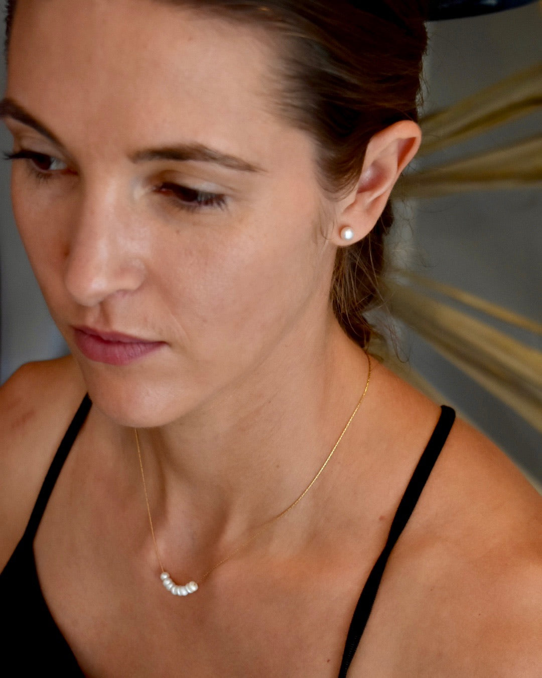 Close-up of a woman wearing a gold necklace and earring.