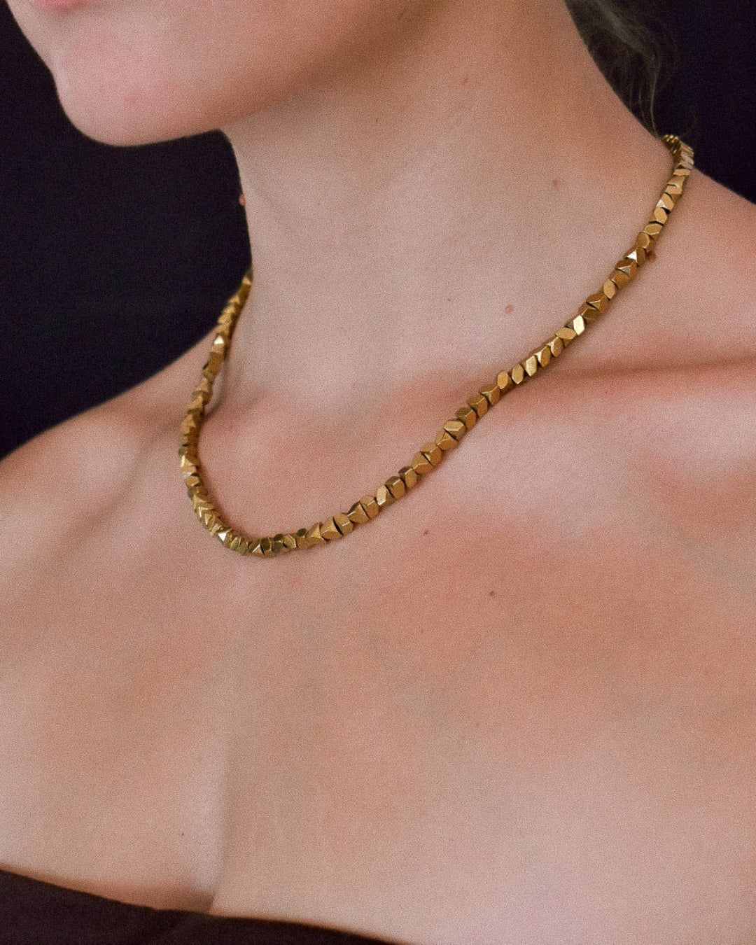 Gold necklace on a person with a black background