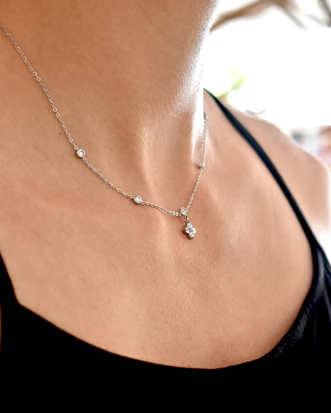 Necklace with small pendants on a person wearing a black top.