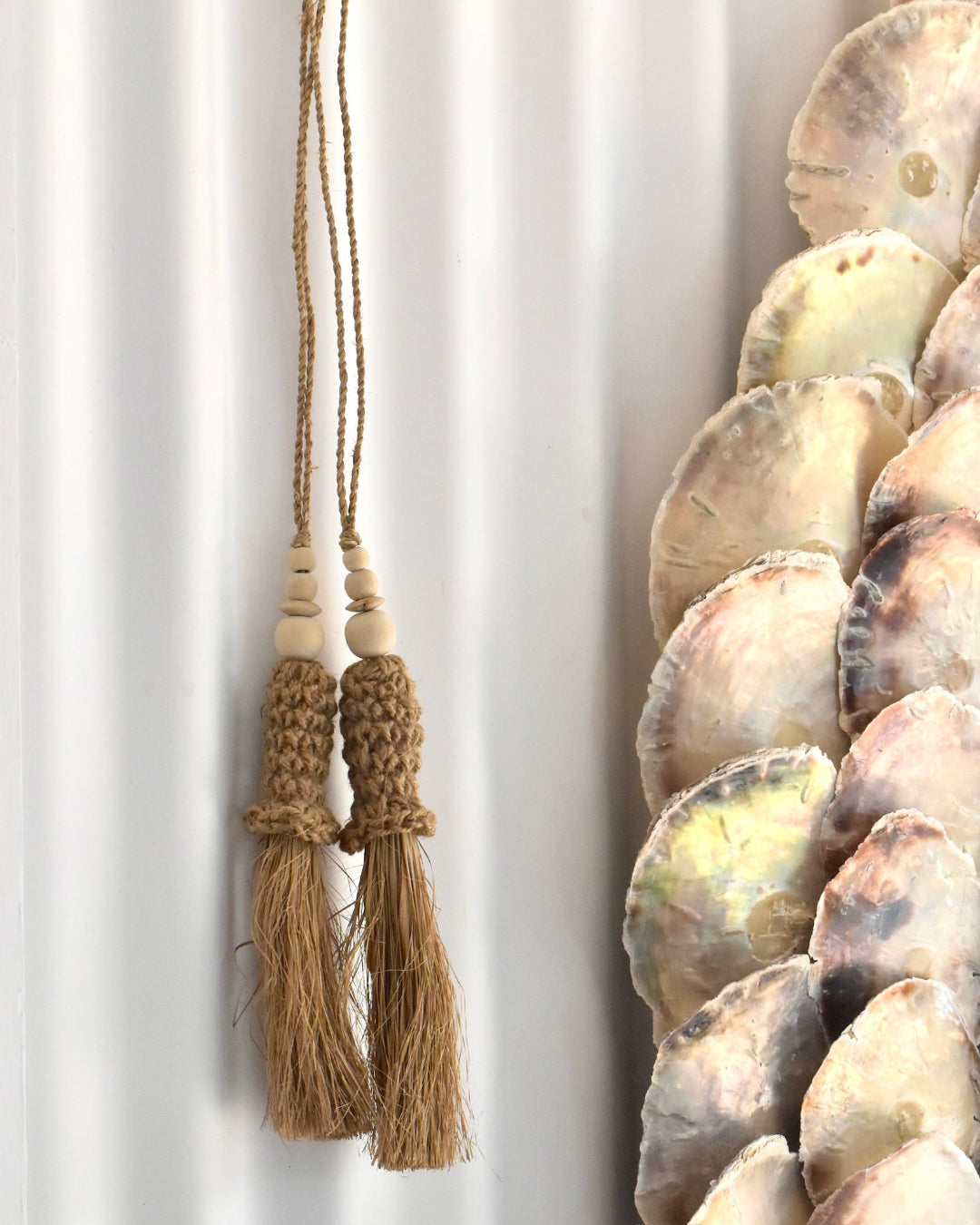 Decorative wall hanging with seashells and tassels on a white background